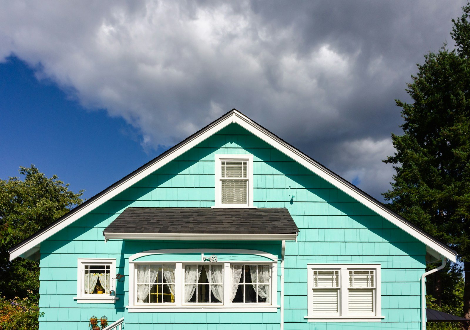 a blue house with white windows and a black roof